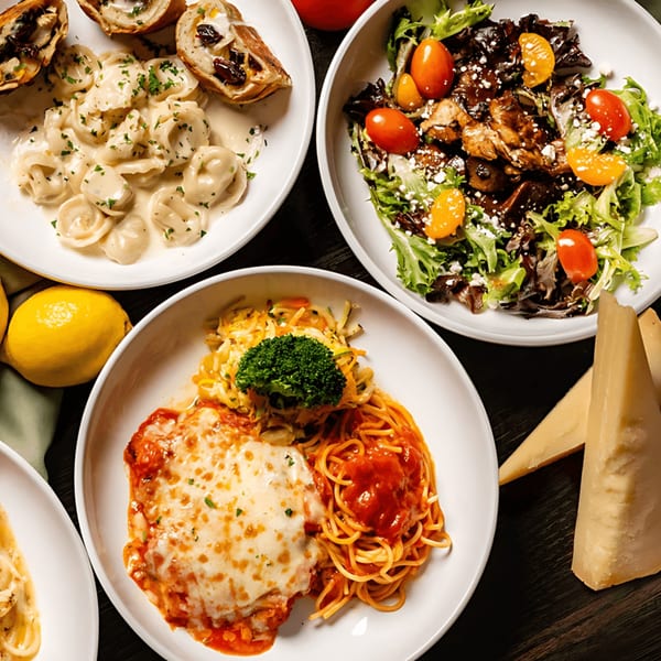 An overhead view of various Italian dishes, including tortellini, salad, chicken parmesan, and spaghetti.