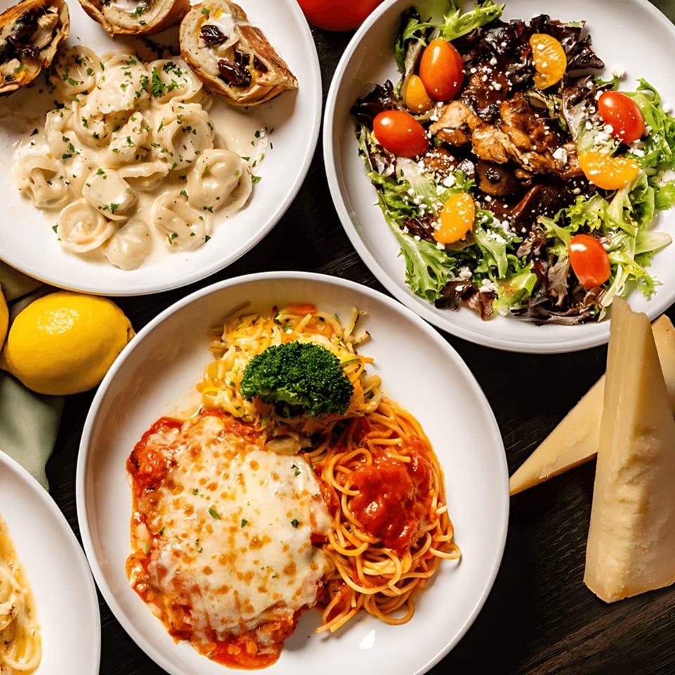 An overhead view of various Italian dishes, including tortellini, salad, chicken parmesan, and spaghetti.