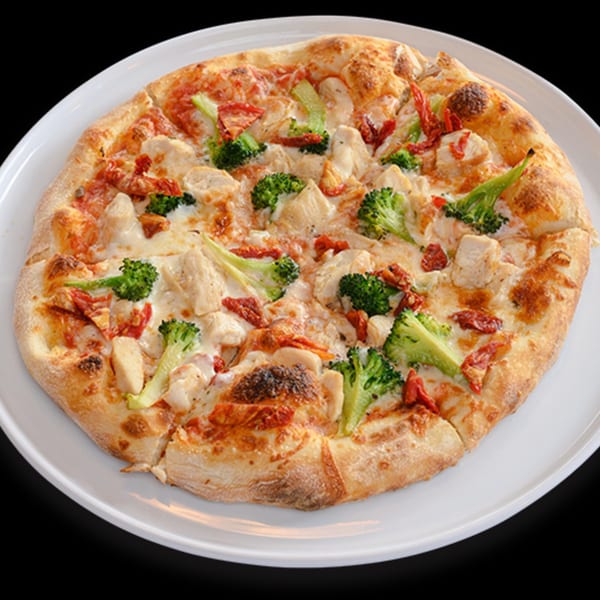Italian chicken, broccoli, and sun-dried tomato pizza on a white plate.